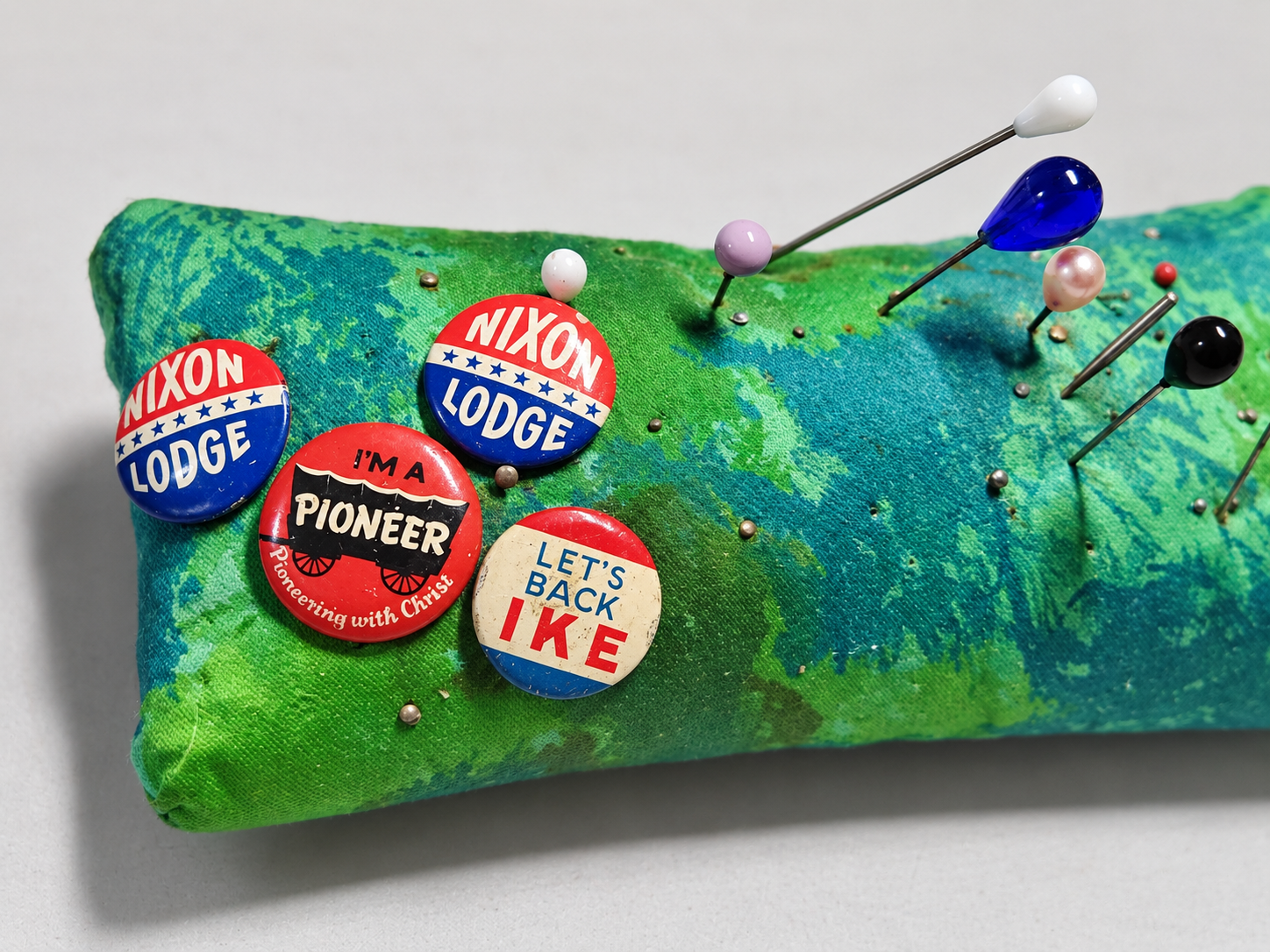 Vintage political pins on a green pincushion