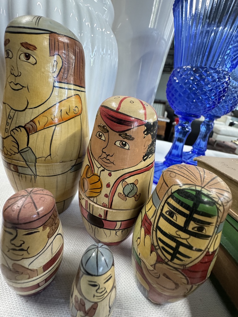 Painted nesting dolls beside blue glassware